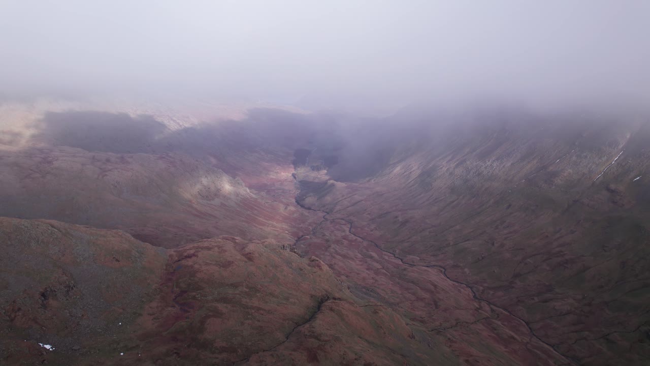 drone disparó volando hacia adelante a través de la niebla con el paisaje debajo, helvellyn, distrito de los lagos, cumbria, reino unido
