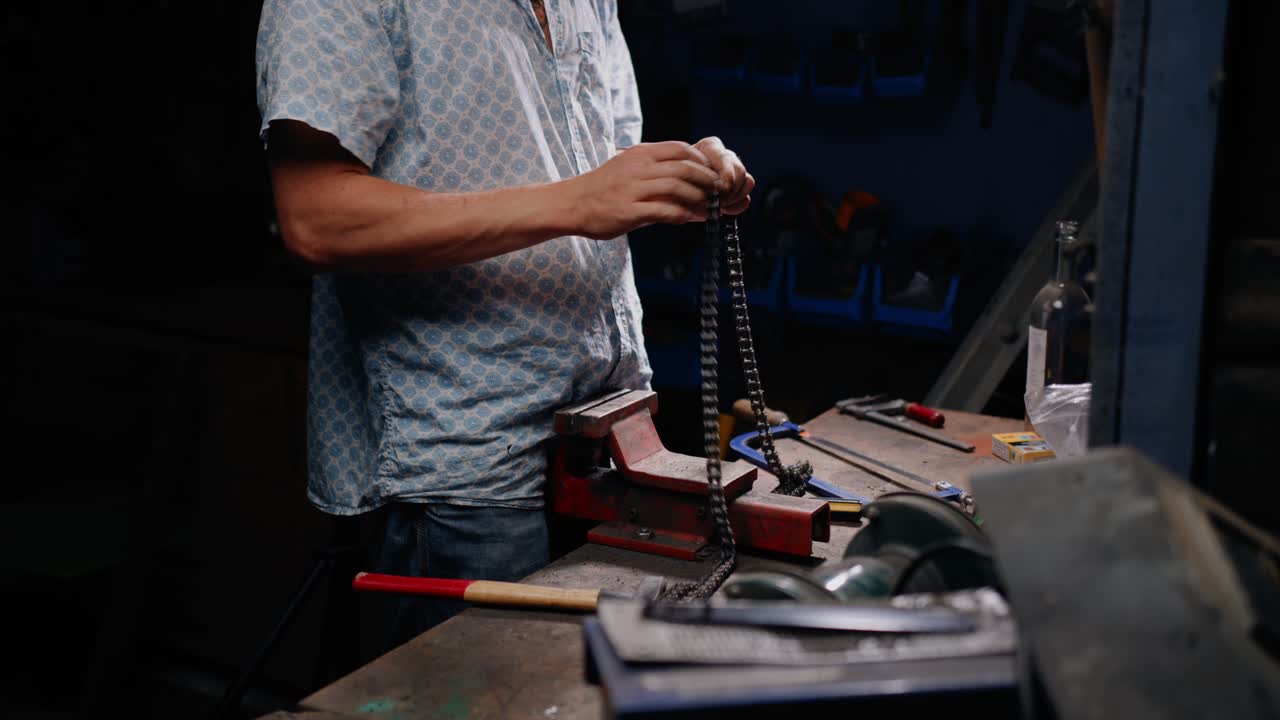 toma cinematográfica de un mecánico manejando una cadena en su banco de trabajo