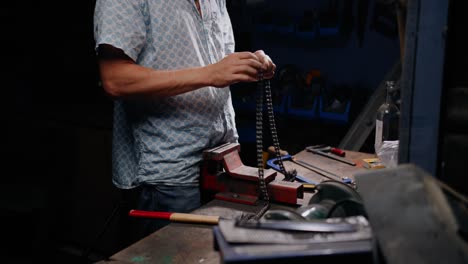 cinematic shot of mechanic handling a chain on his workbench