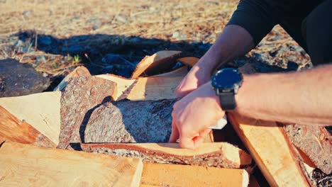 a person is burning freshly cut firewood to turn it into charcoal - close up
