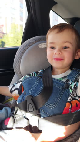 adorable smiling caucasian toddler sitting in the baby chair car seat. happy child rejoicing a ride.