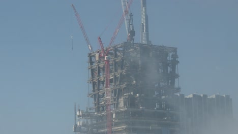 Aufnahme-Eines-Riesigen-Wolkenkratzers,-Der-Vor-Dem-Höchsten-Gebäude-Der-Welt,-Dem-Burj-Khalifa-In-Dubai,-Gebaut-Wird