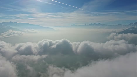 fluffy skyscape above mountain range with shining sun, aerial view