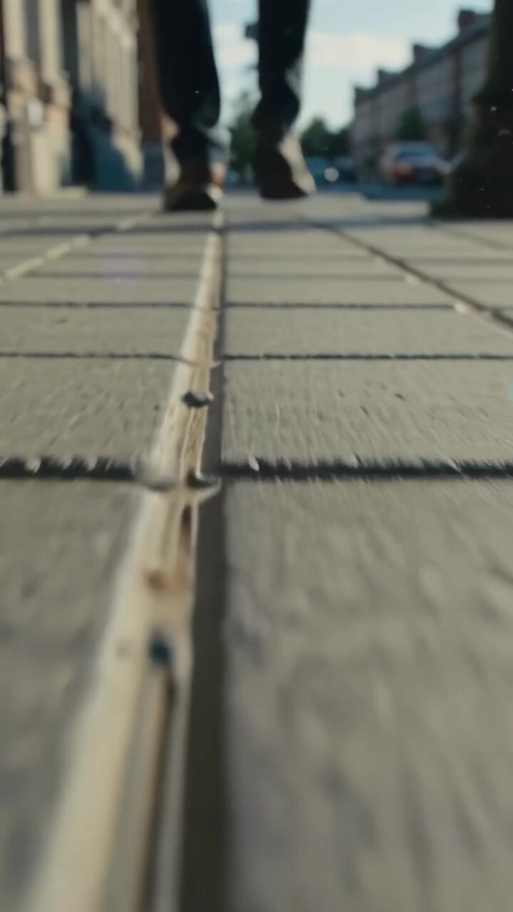 Vertical video: Tracking walker stepping on sidewalk from grout closeup start, showing dark shoes