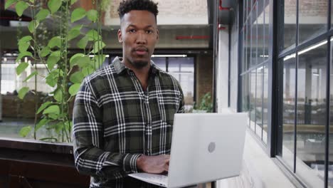 happy african american male creative using laptop at casual office, in slow motion