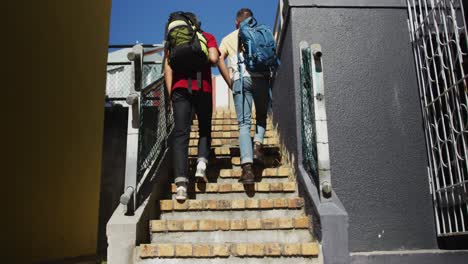 back view of two mixed race male friends walking upstairs and talking