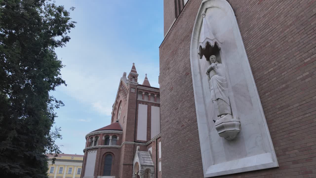 Scenic footage capturing the Votive Church in Szeged with surrounding gardens and a detailed marble statue