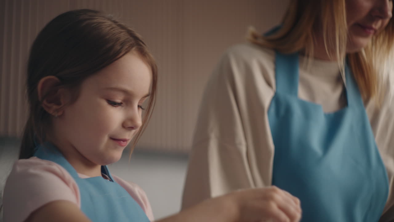 una niña bonita está ayudando a su madre en la cocina. el niño está jugando con pasteles crudos y sonriendo encantadoramente.