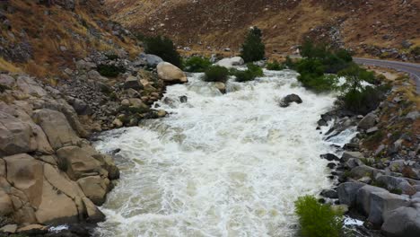 Inclinación-Panorámica-Hacia-Arriba-Sobre-Una-Cascada-Furiosa-En-El-Río-Kern-Que-Baja-Del-Lago-Isabella,-California,-El-Agua-Corre-Dura-Y-Peligrosa