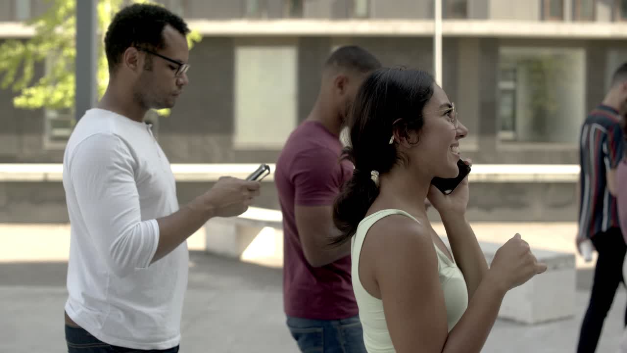 vista lateral de una mujer emocionada hablando por teléfono en la multitud