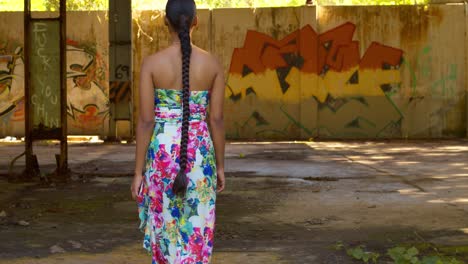 a model walks toward grafitti art on the wall at an abandoned warehouse