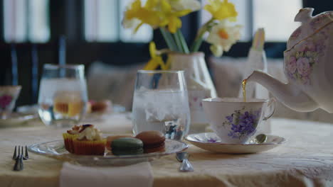 Classy-tea-table-set-with-beautiful-yellow-flowers,-colorful-pastries-and-vintage-teaware