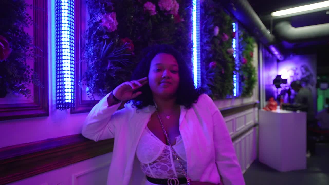 smiling lady in a bar with pink led lights.