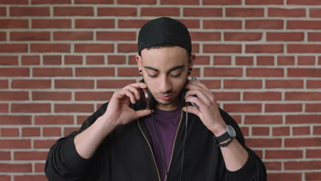 attractive young hispanic man portrait of student listening to music on headphones using phone