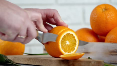 male hands slicing a ripe orange into round slices.