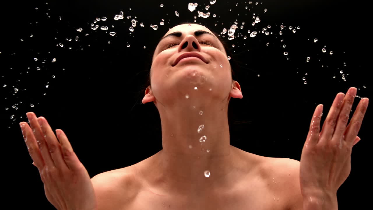 una joven bonita salpicándose la cara con agua.