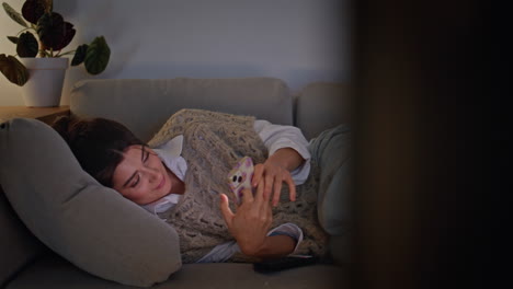 happy girl relaxing couch typing smartphone at night home closeup. woman resting