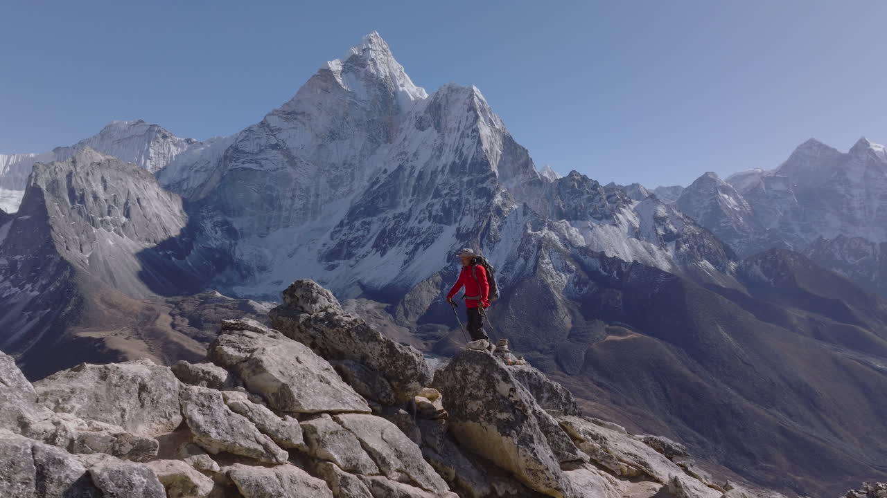 Un turista fa un'escursione verso la cima del Picco Nangkartshang a Dingboche, godendosi ampie vedute himalayane con l'Ama Dablam e le catene montuose del Khumbu nella regione dell'Everest in Nepal.