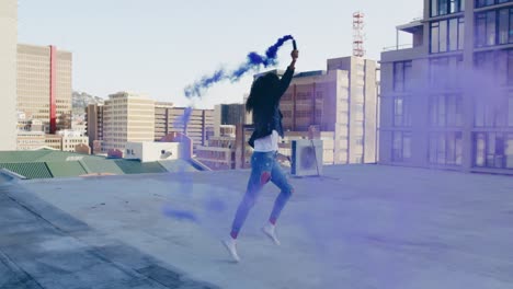 mujer joven de moda en el techo urbano usando una granada de humo