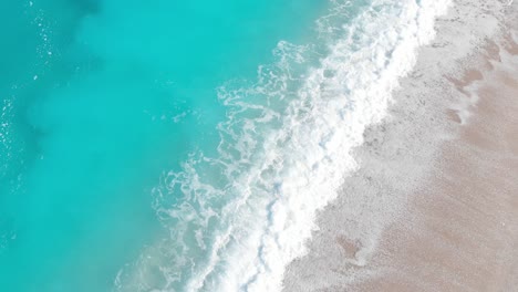 drone shot of waves crashing on an empty sandy beach