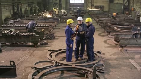 ingenieros discutiendo un proyecto en una planta de fabricación de metales