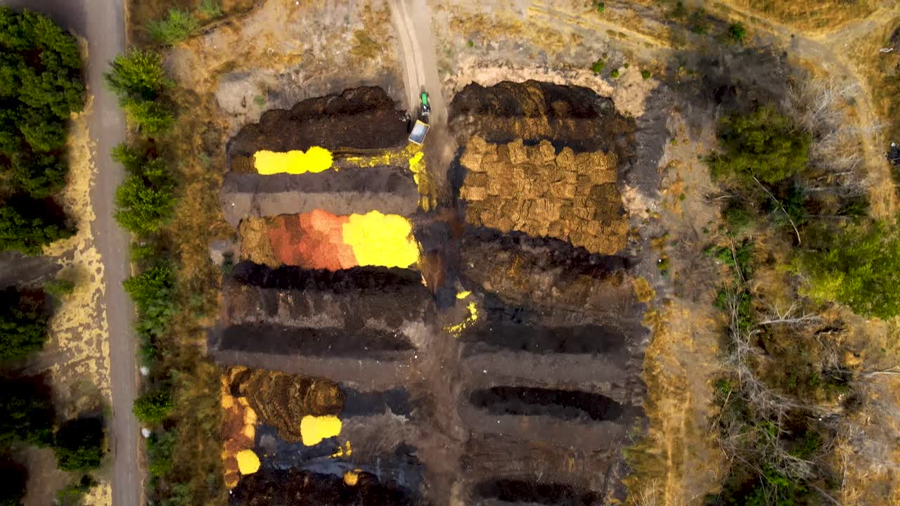 Aerial top down dolly in of orange shells discarded in a compost area surrounded by plantations in a farm field at daytime