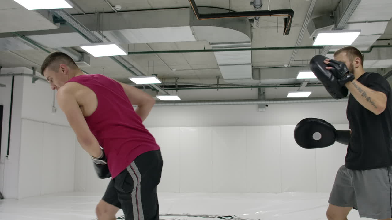 kickboxer는 트레이너와 함께 우드라의 경사와 발바닥의 다이브를 느린 동작으로 수행합니다.