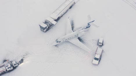 embraer business jet sobre asfalto nevado con vehículos de apoyo, antena
