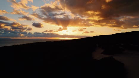 Rising-aerial-view-of-a-glowing-orange-sunset-off-of-Spain's-coast