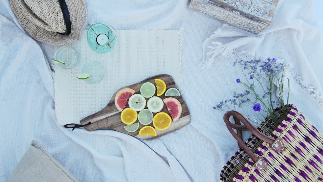 Placing A Wooden Chopping Board With Slices Of Tropical Citrus Fruits at a Luxury Picnic in the Countryside on Holiday - flat lay top shot
