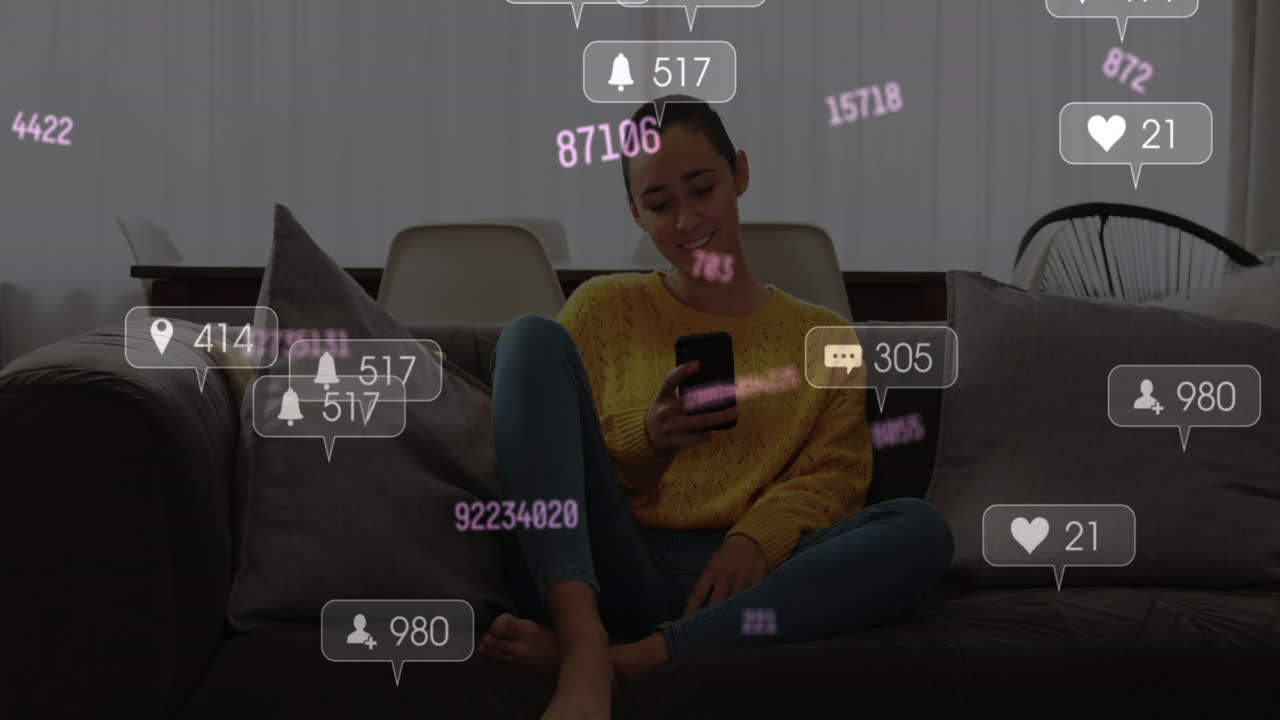 animación de iconos de las redes sociales sobre una mujer biracial sonriendo mientras usa un teléfono inteligente en casa