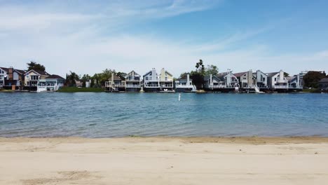 slider shot, stunning view of villa cottages built on clear blue lagoon in parkside aquatic park, san mateo, california sandy beach