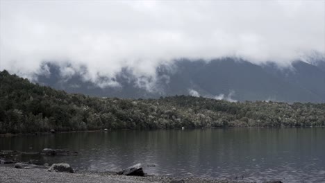 lake surrounded by mountains and forest under cloudy sky