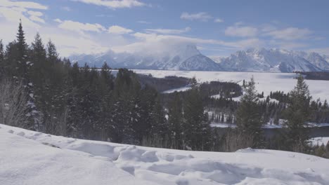 handheld panning shot of the teton range with snow and the snake river in the foreground