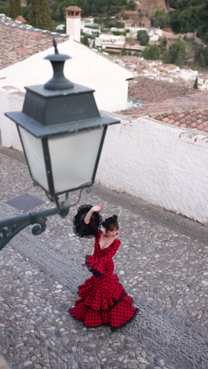 Bailaora de flamenco con vestido rojo de lunares actuando en una calle empedrada