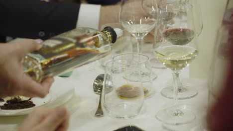 Italian-Grappa-digestif-brandy-being-served-into-crystal-glasses-at-dinner-party