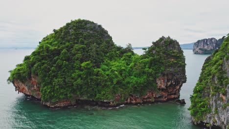 limestone island along the coastal lands of thailand in railay from an aerial orbital drone shot