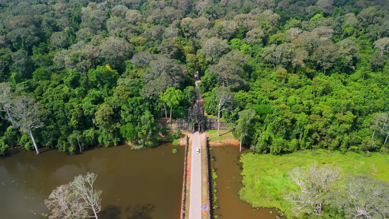 Um drone se aproxima do Portão da Vitória em Angkor Thom e, em seguida, voa para cima, em uma vista de cima da ponte e da floresta