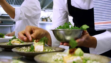 male chef garnishing appetizer plates at order station 4k