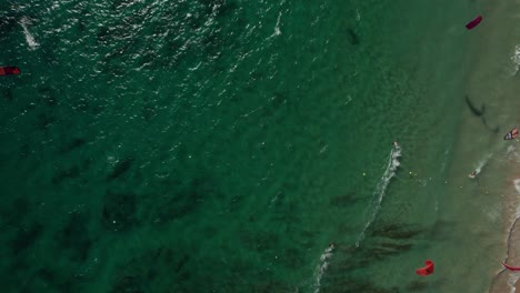 overhead-aerial-view-of-many-kitesurfers-doing-practice-and-having-fun-at-Tarifa-Beach,-Cadiz,-spain