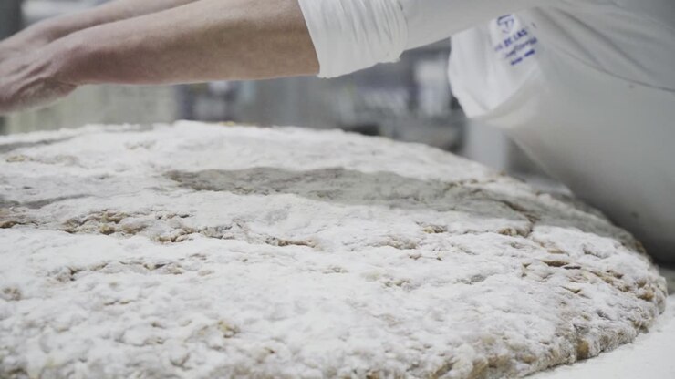 Slow motion panning close up shot of women hands of a baker in a candy factory in Medina Sidonia preparing a dough for candy with flour