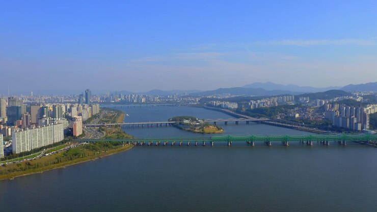 Ripresa con drone in avanti sopra il fiume Han verso un ponte nella città di Seoul in una giornata di sole.