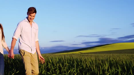 romantic couple holding hands while walking in field