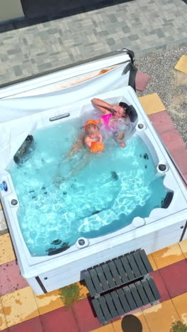 vertical drone shot of a mom and son relaxing in a jacuzzi, bright, sunny day