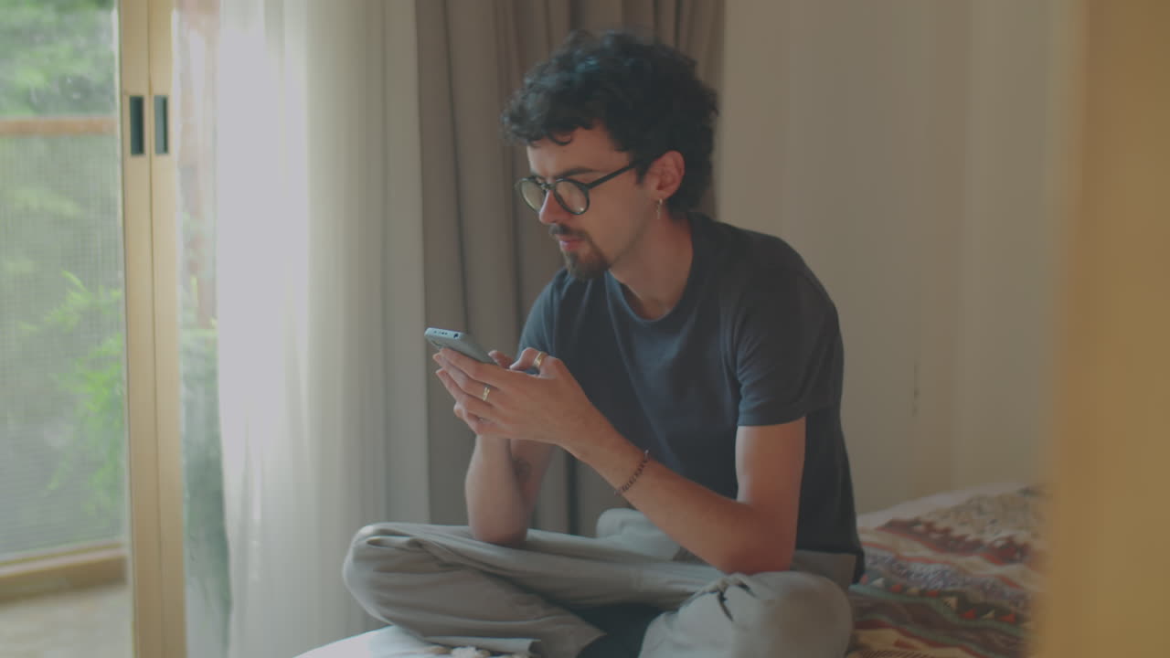 Man Sitting on Bed and Using Phone at Home