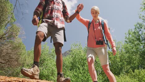happy diverse couple hiking with backpacks in park, slow motion