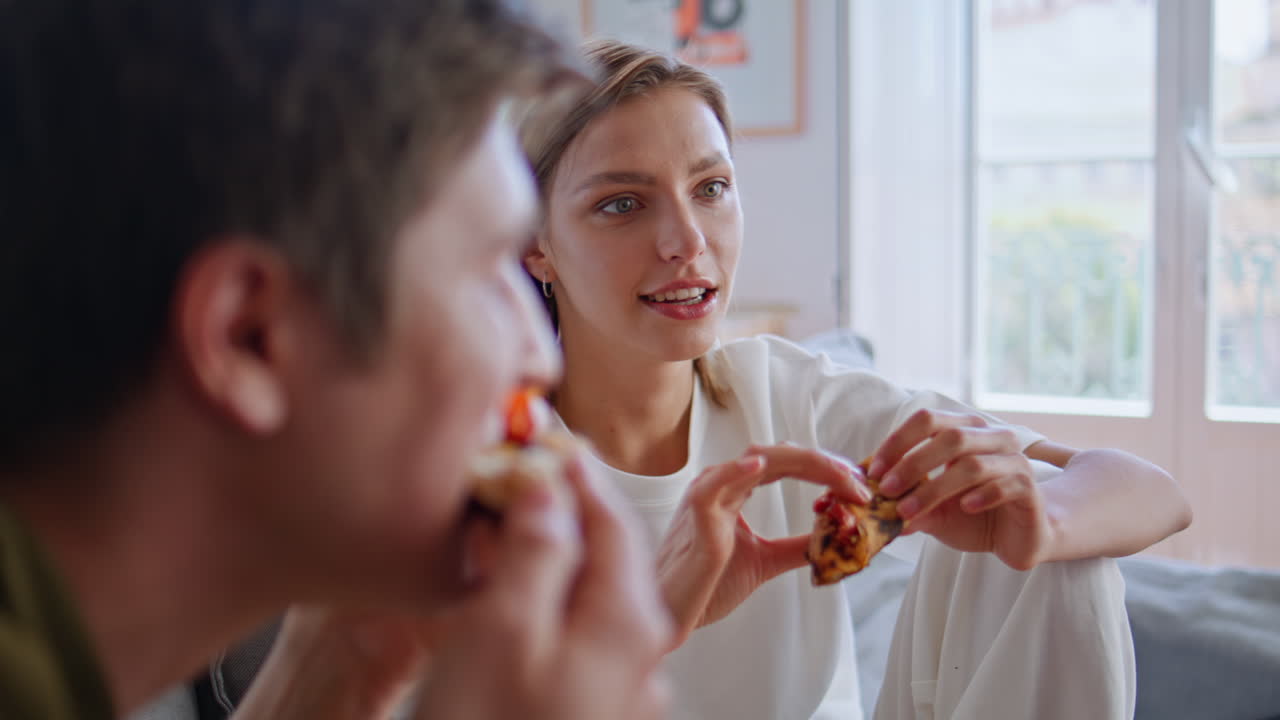 Best friends chewing pizza spending weekend on cozy couch closeup. Woman talking