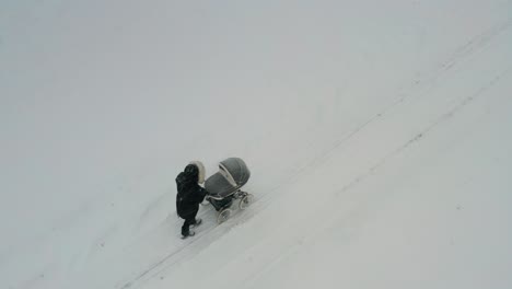 aerial view of mother walk with baby carriage on snowy countryside road