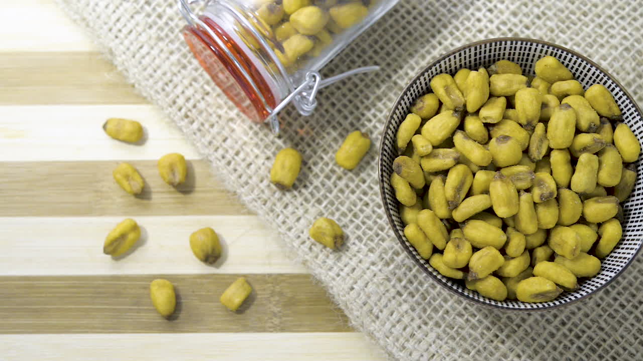 헤시안 천으로 줄무늬 테이블에 건포도 밤나무 혼합물로 채워진 유리병 세라믹 그릇을 통해 천천히 패닝 샷 위에서 아래로 보기