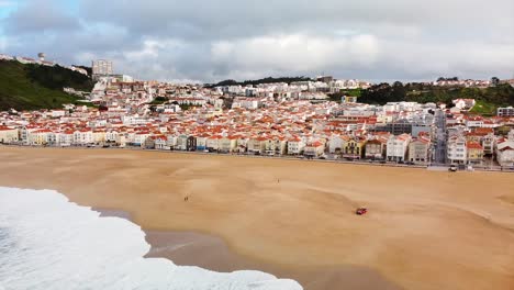 Aerial-View-Of-Nazare-Beach-And-Town-Building-In-Background